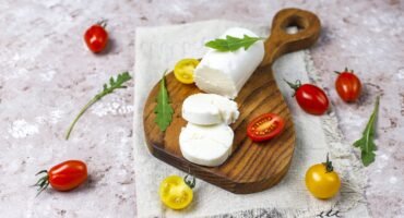 Goat Cheese Slices on Wooden Board with ruccola,cherry tomatoes.
