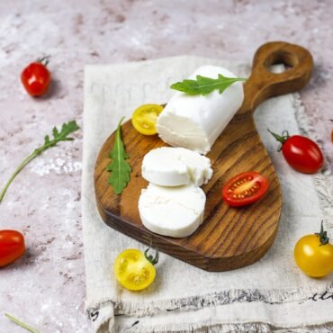 Goat Cheese Slices on Wooden Board with ruccola,cherry tomatoes.
