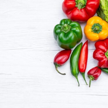 top-view-green-salad-along-withful-bell-peppers-spicy-peppers-white-desk-vegetable-food-meal
