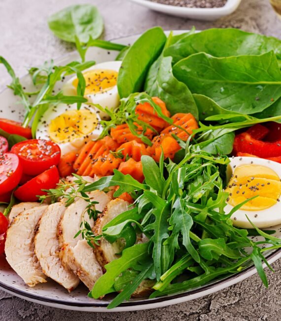 healthy-food Plate with a keto diet food. Cherry tomatoes, chicken breast, eggs, carrot, salad with arugula and spinach. Keto lunch